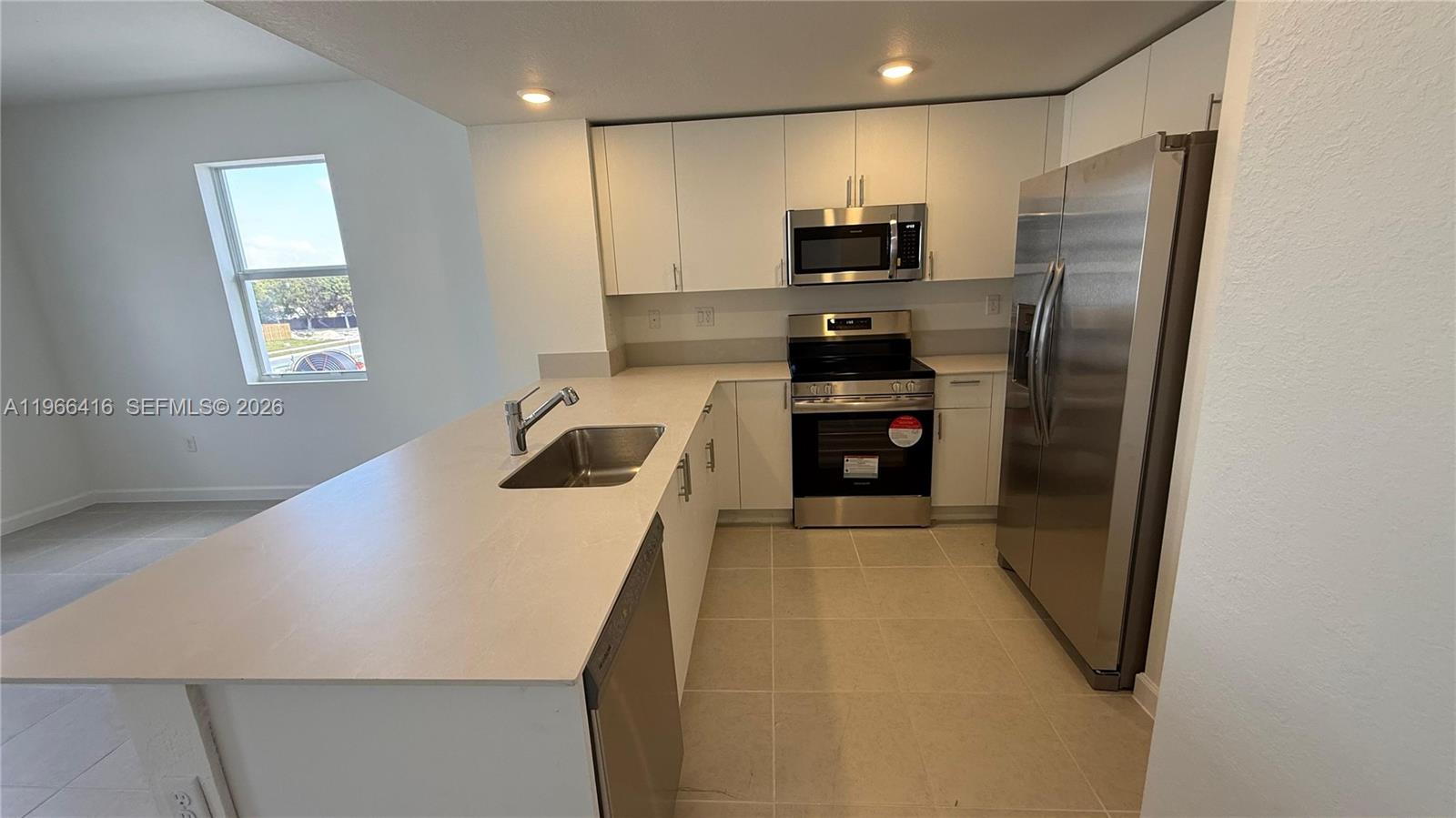 12420 Southwest 248th Street, Unit 10 Homestead, FL 33032 - Photo 6 of 16 a kitchen with stainless steel appliances a refrigerator sink and stove