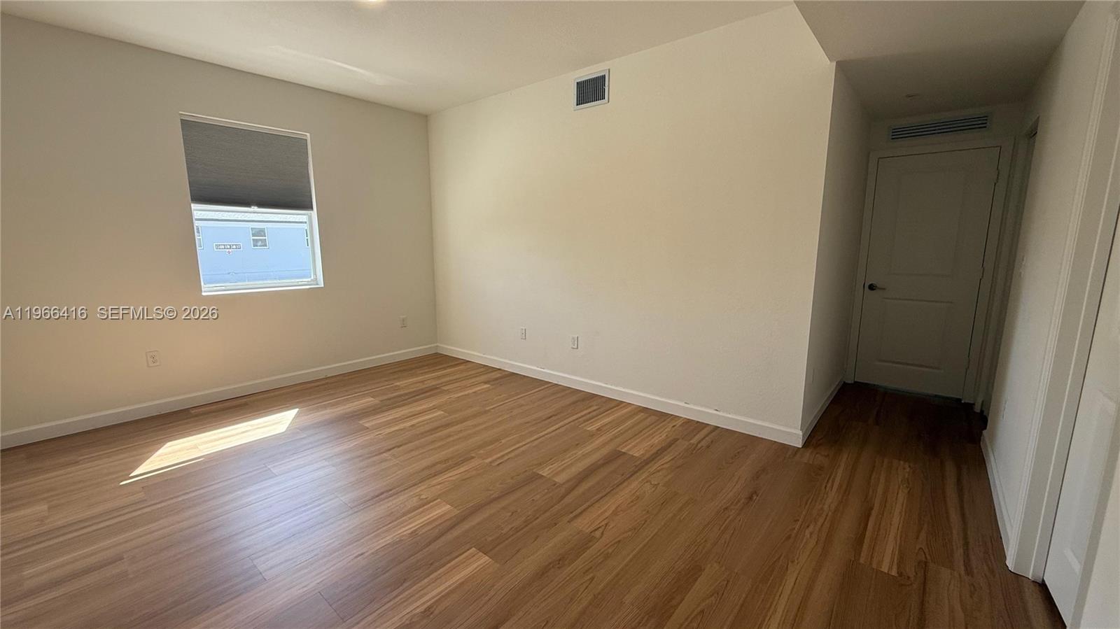 12420 Southwest 248th Street, Unit 10 Homestead, FL 33032 - Photo 10 of 16 a view of an empty room with wooden floor and a window