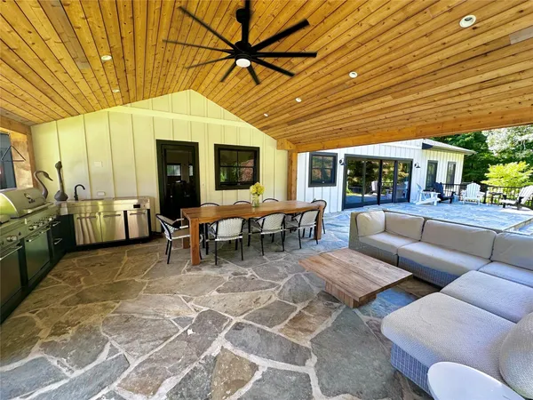 a view of a patio with couches table and chairs under an umbrella