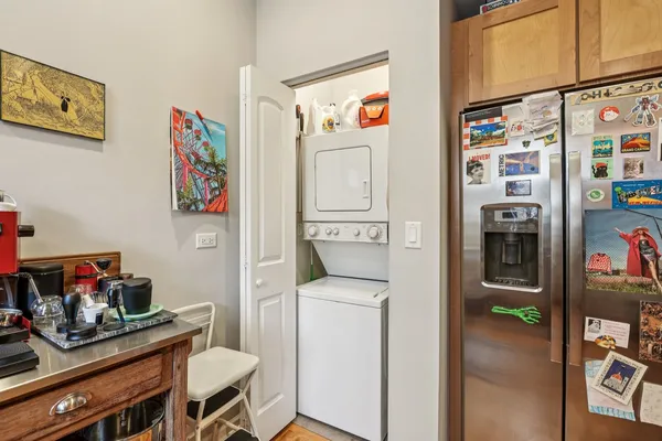 a utility room with fridge and wooden floor