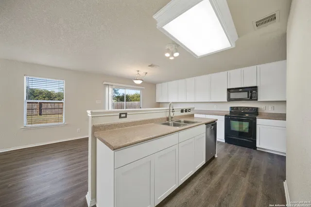 a kitchen with a sink stove and wooden floor