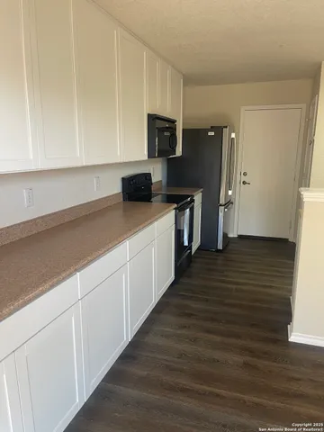 a kitchen with cabinets stainless steel appliances a sink and wooden floor