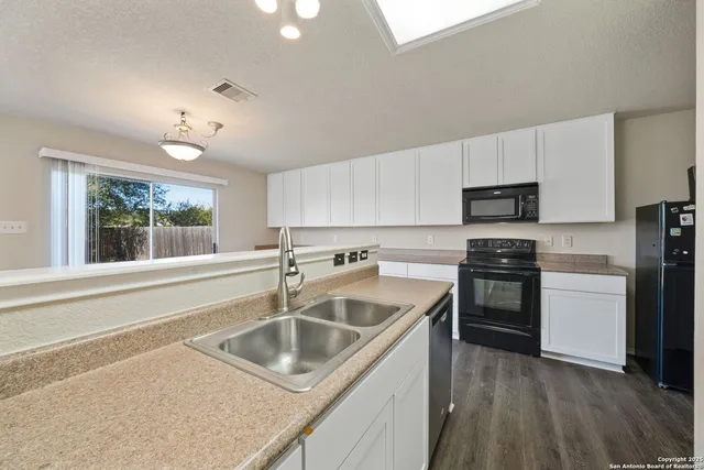 a kitchen that has a sink cabinets counter space stainless steel appliances and a window