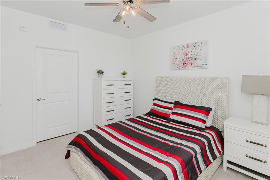 6034 National Boulevard, Unit 528 Ave Maria, FL 34142 - Photo 23 of 43 a bedroom with a bed and a chandelier