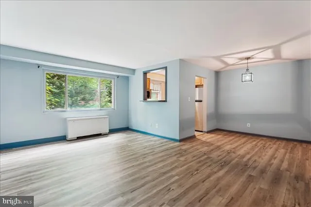 a view of an empty room with wooden floor and a window