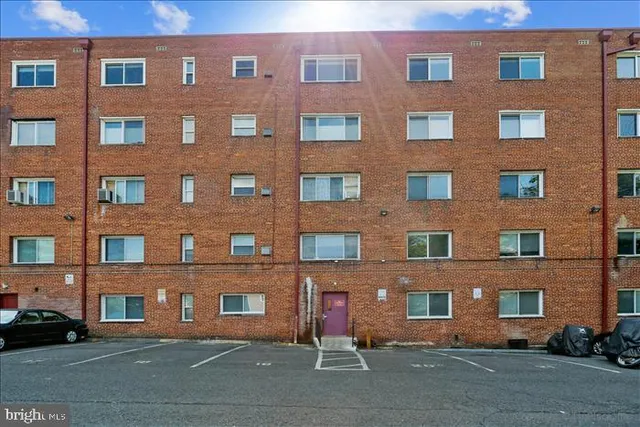a side view of a building with cars parked