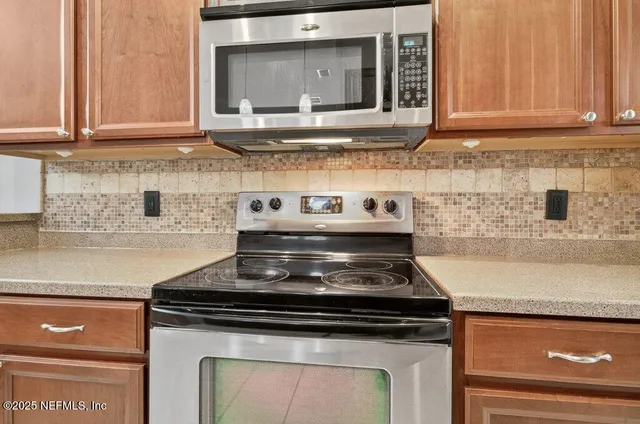 a kitchen with stainless steel appliances granite countertop a stove top oven a sink dishwasher a dining table and chairs with wooden floor