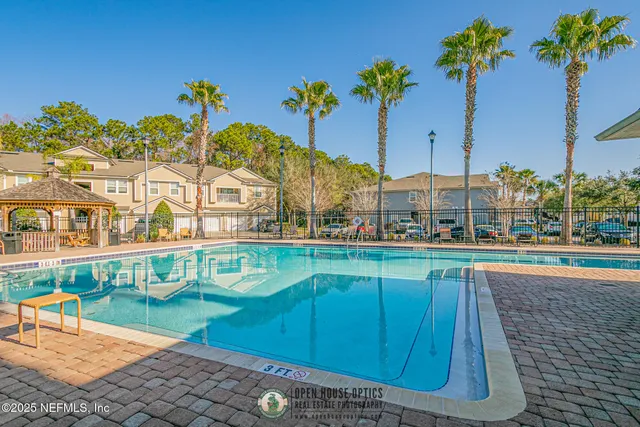 a view of a swimming pool with a lawn chairs under an umbrella