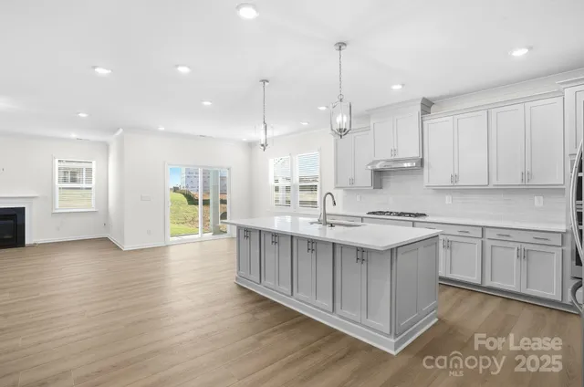 a large kitchen with stainless steel appliances kitchen island a large counter top and a wooden floors