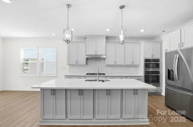 a kitchen with kitchen island granite countertop a sink refrigerator and cabinets