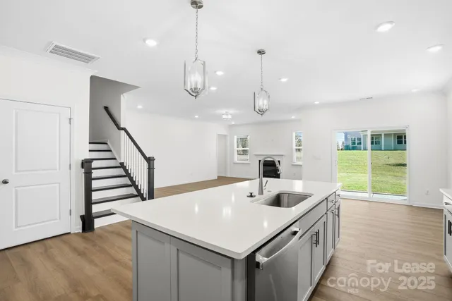 a kitchen with stainless steel appliances kitchen island granite countertop a sink and a large window with wooden floor