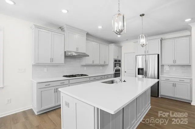 a kitchen with kitchen island a sink a stove a refrigerator and white cabinets