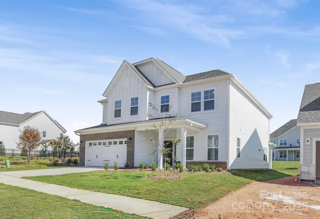 a view of a white house next to a yard with big trees