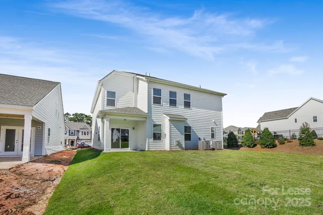 a view of a big yard in front of a brick house with many windows