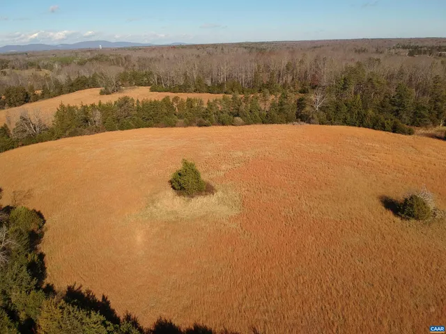 an aerial view of a house with a yard and trees in the background