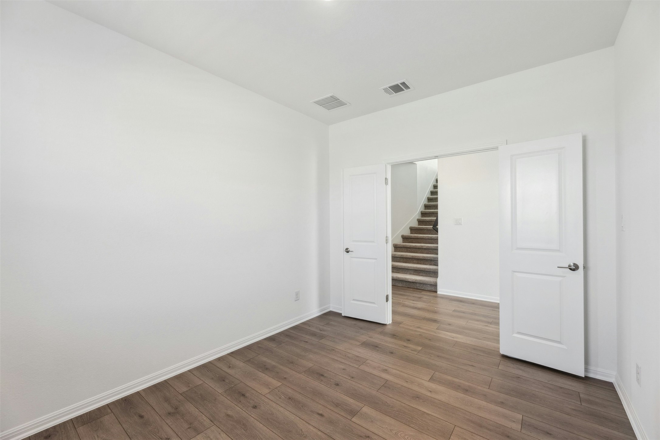 2001 Wynn Road Hutto, TX 78634 - Photo 23 of 39 Laminate flooring extends into a versatile room, offering direct access to the carpeted staircase.