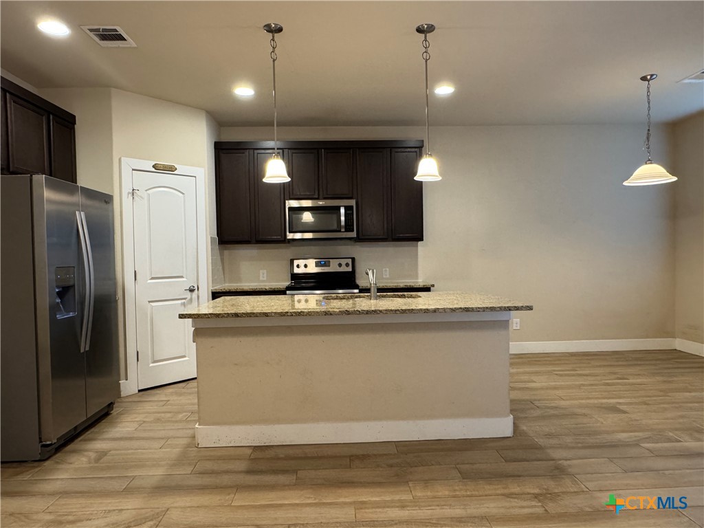 523 High Tech Drive Georgetown, TX 78626 - Photo 3 of 11 a view of a kitchen with stainless steel appliances granite countertop a refrigerator a sink a stove and a microwave