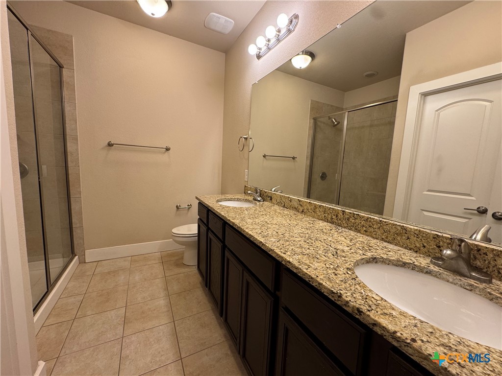 523 High Tech Drive Georgetown, TX 78626 - Photo 7 of 11 a bathroom with a granite countertop sink a mirror and a toilet