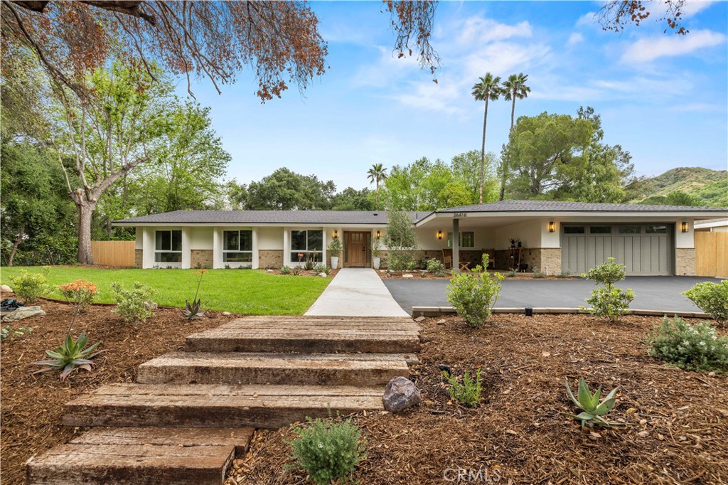 a front view of a house with a yard and potted plants