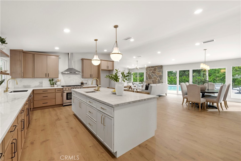 26418 Sand Canyon Road Canyon Country, CA 91387 - Photo 15 of 70 a kitchen with stainless steel appliances granite countertop a stove top oven a sink dishwasher a dining table and chairs with wooden floor