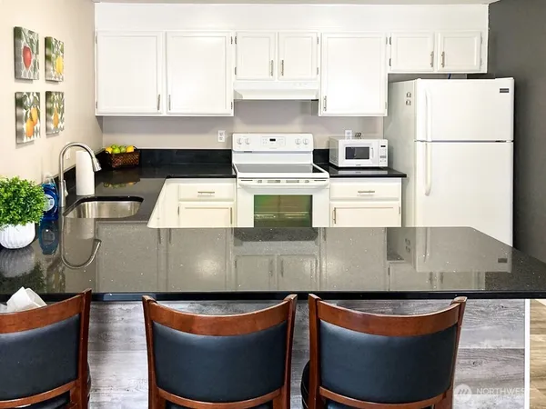 a kitchen with granite countertop a sink a stove and white stainless steel appliances