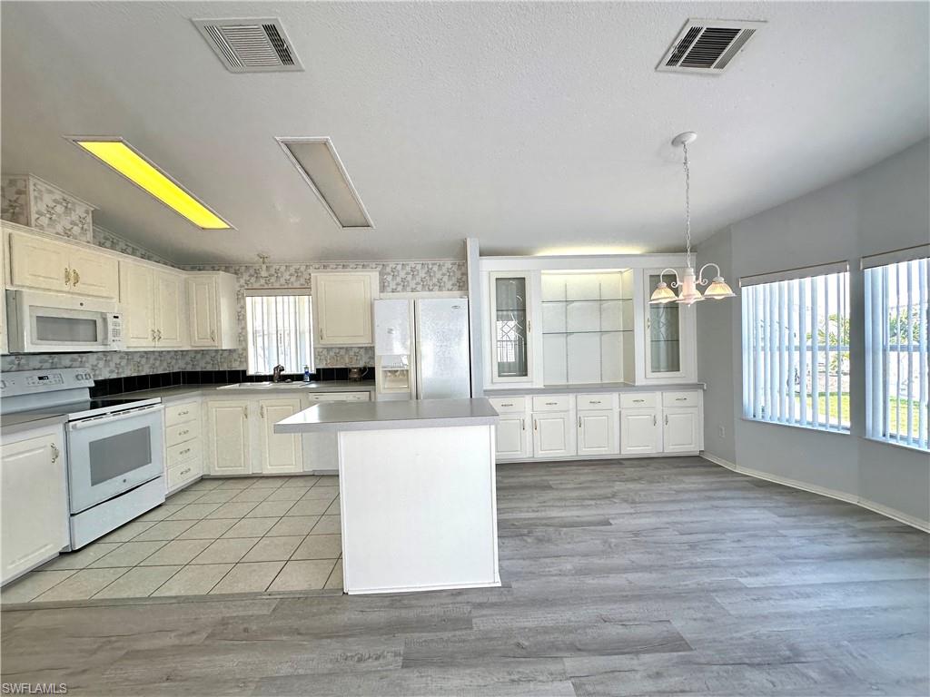 4551 Mayflower Way East Estero, FL 33928 - Photo 13 of 20 a large kitchen with cabinets and wooden floor
