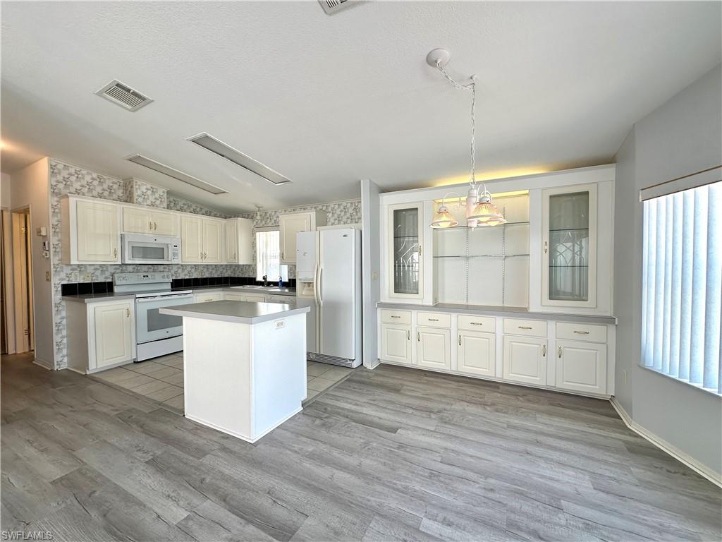 4551 Mayflower Way East Estero, FL 33928 - Photo 9 of 20 a kitchen with white cabinets and white appliances