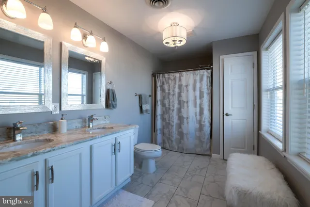a spacious bathroom with a double vanity sink toilet and a tub