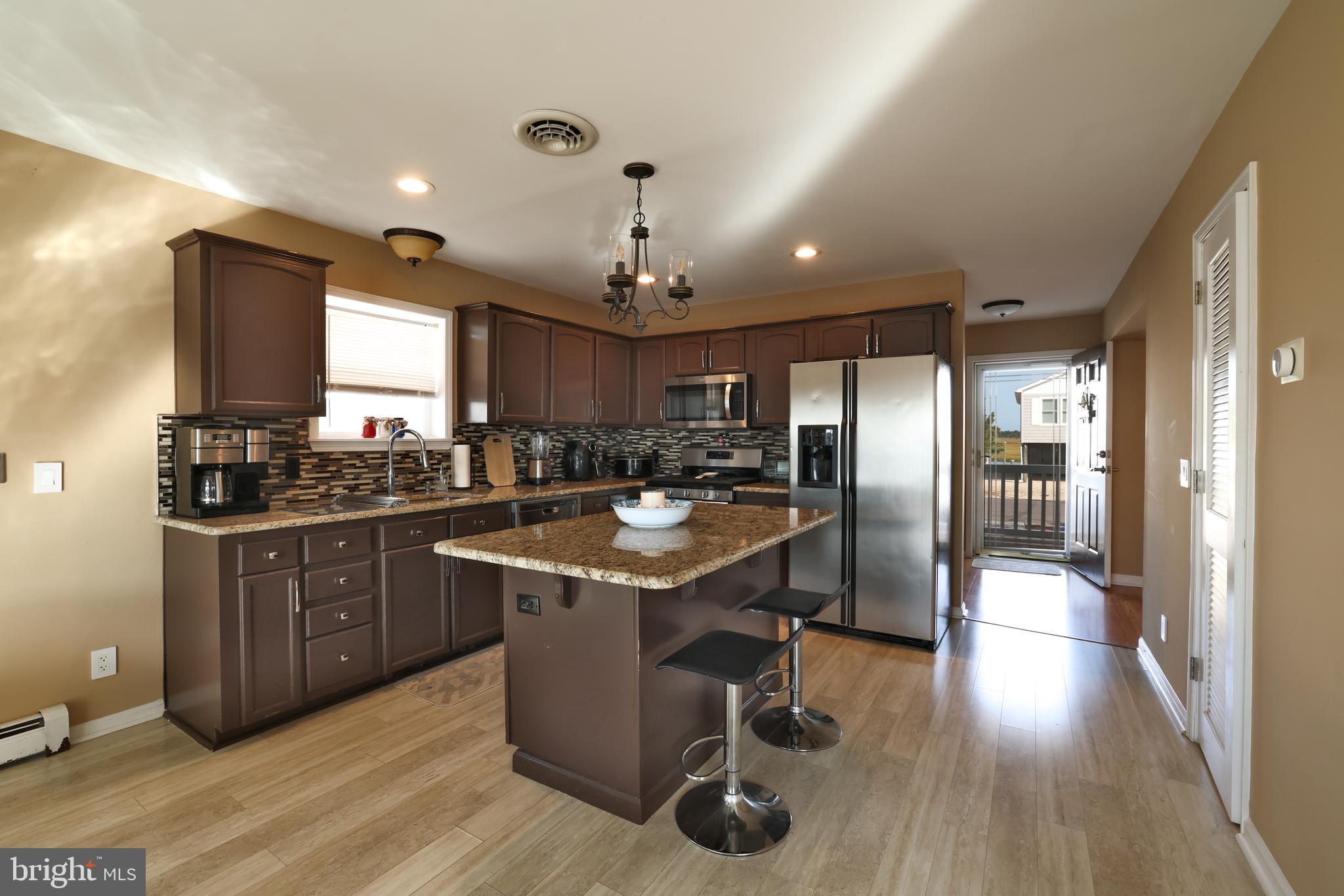 348 Kingfisher Road Tuckerton, NJ 08087 - Photo 4 of 37 a kitchen with stainless steel appliances granite countertop a refrigerator a sink dishwasher a stove and a dining table with wooden floor