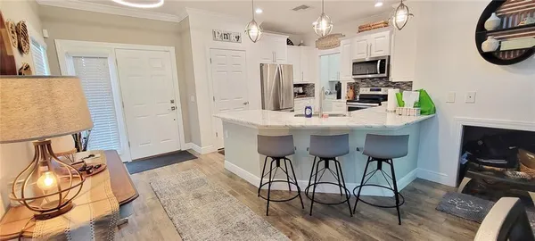 a kitchen with stainless steel appliances kitchen island a table chairs in it and a wooden floors