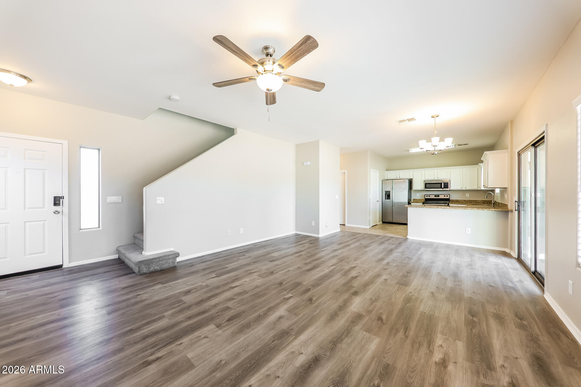 6716 South 36th Lane Phoenix, AZ 85041 - Photo 3 of 22 a view of empty room with wooden floor and kitchen view