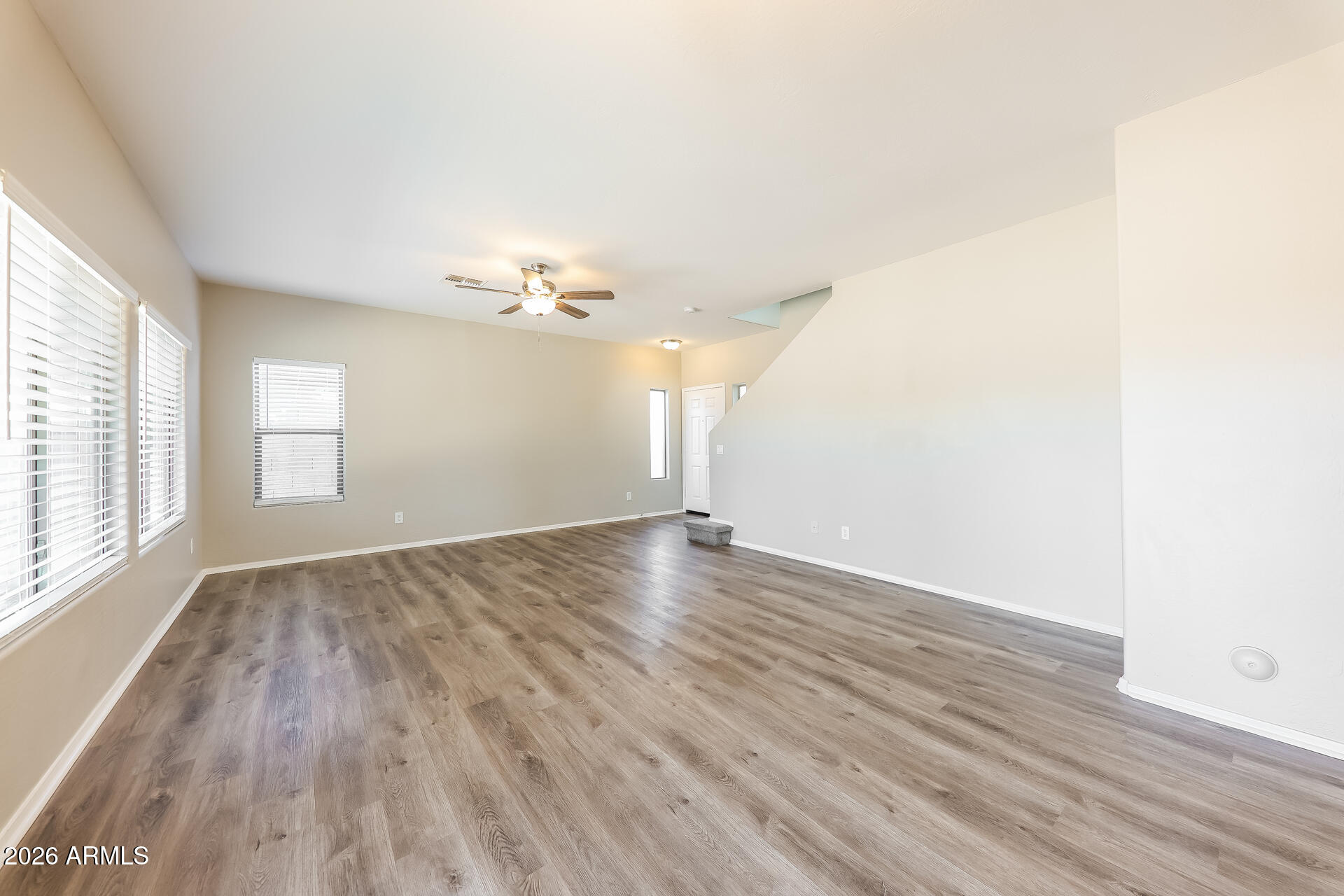 6716 South 36th Lane Phoenix, AZ 85041 - Photo 4 of 22 an empty room with wooden floor and windows