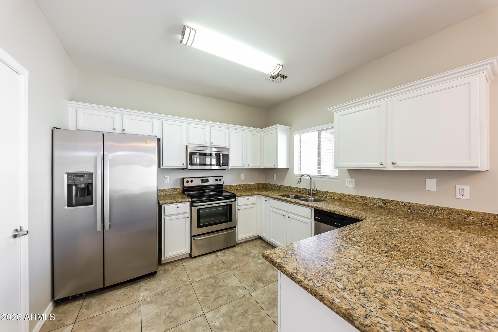 6716 South 36th Lane Phoenix, AZ 85041 - Photo 6 of 22 a kitchen with granite countertop stainless steel appliances and white cabinets