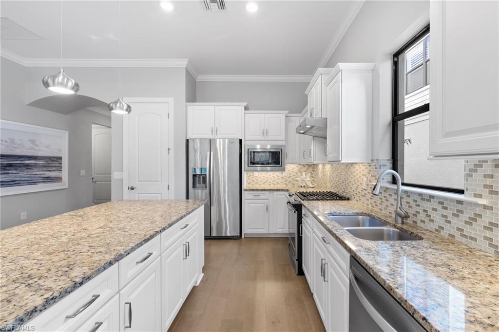 9410 Whooping Crane Way Naples, FL 34120 - Photo 11 of 38 a kitchen with stainless steel appliances granite countertop a sink stove and refrigerator