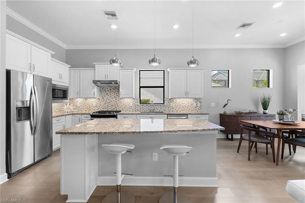 9410 Whooping Crane Way Naples, FL 34120 - Photo 13 of 38 a kitchen with cabinets table and chairs