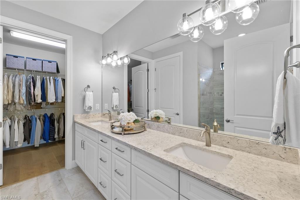 9410 Whooping Crane Way Naples, FL 34120 - Photo 21 of 38 a bathroom with double vanity sinks a vanity a lamp and a mirror