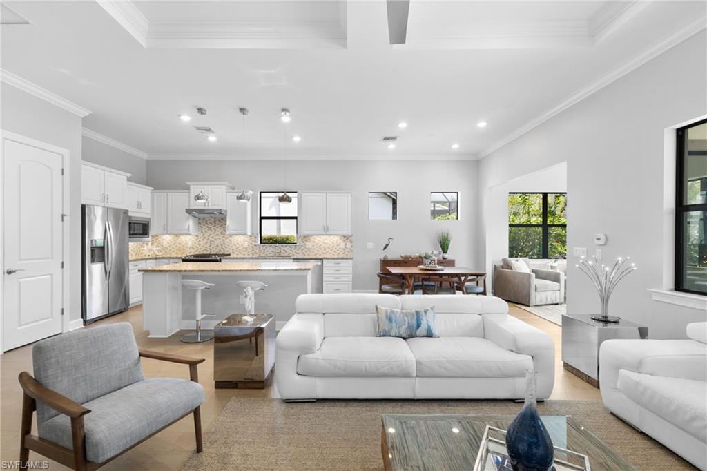 9410 Whooping Crane Way Naples, FL 34120 - Photo 4 of 38 a living room with furniture white walls and kitchen view