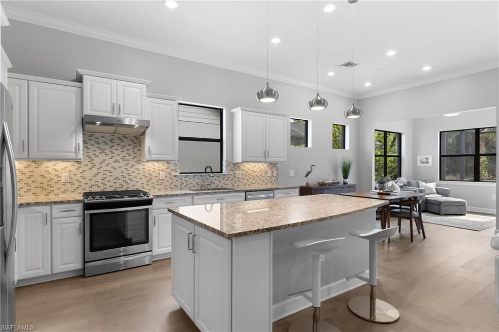9410 Whooping Crane Way Naples, FL 34120 - Photo 7 of 38 a kitchen with stainless steel appliances granite countertop a stove oven and a refrigerator