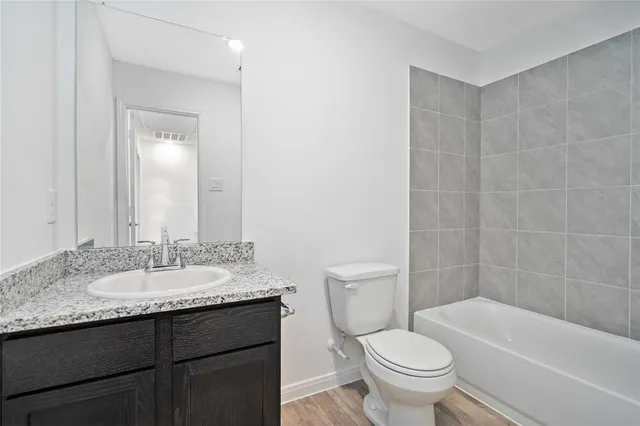 a bathroom with a granite countertop toilet a sink and a bathtub