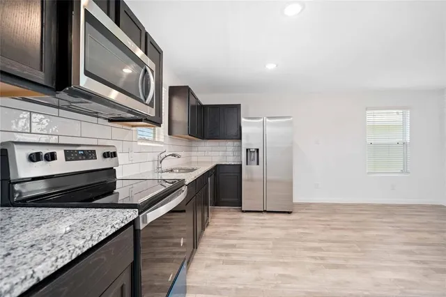 a kitchen with stainless steel appliances granite countertop a stove a sink and a refrigerator