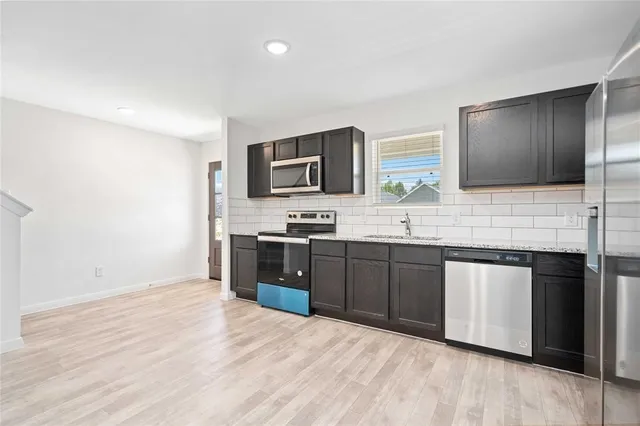 a large kitchen with stainless steel appliances granite countertop a stove a sink and a microwave