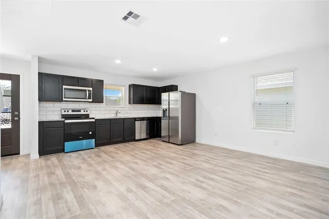 a large kitchen with stainless steel appliances kitchen island a large counter top and oven