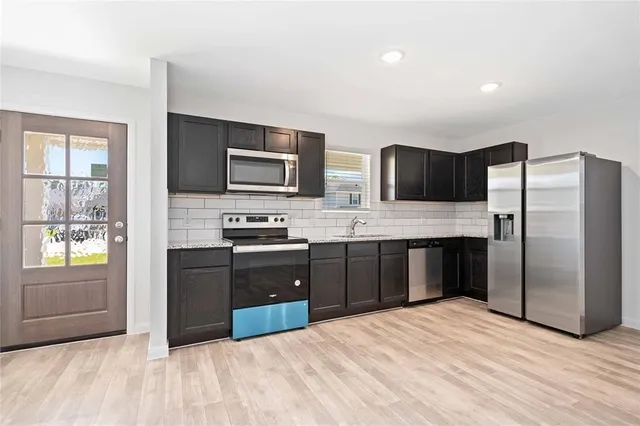 a kitchen with granite countertop a refrigerator and a stove top oven