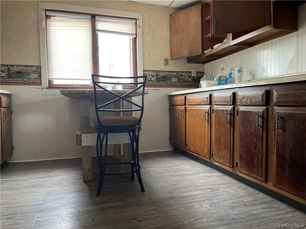 a kitchen with stainless steel appliances wooden floor and chair