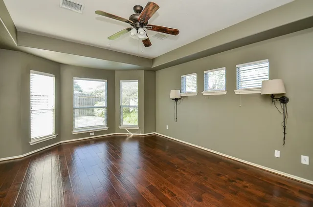 a view of an empty room with window and wooden floor