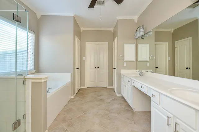 a spacious bathroom with a double vanity sink a mirror a bathtub and next to a window