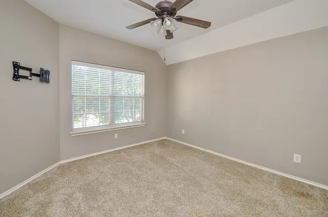 an empty room with a window and a fan