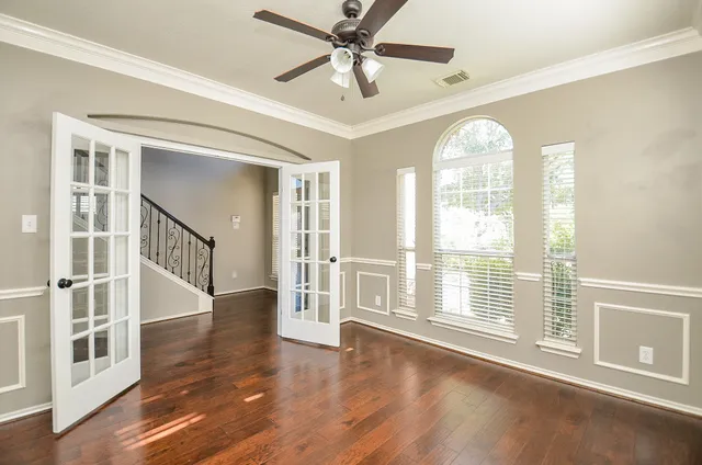 a view of an empty room with wooden floor and a window