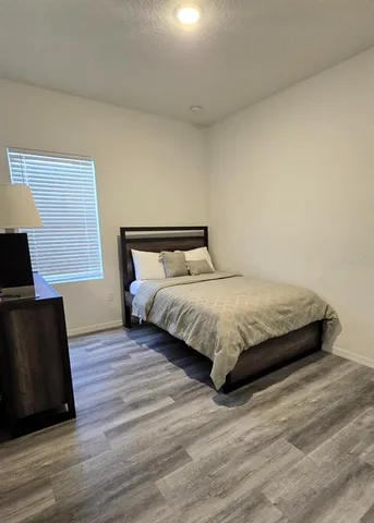 a large bed sitting in a bedroom next to a lamp with wooden floor