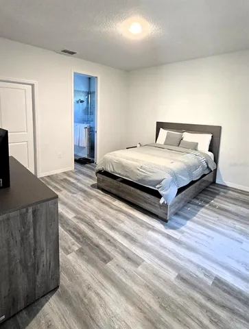 a spacious bedroom with a bed and wooden floor